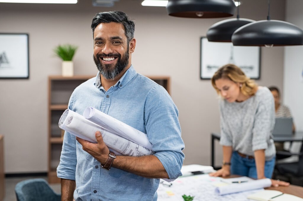 multiethnic architect with blueprints in creative office.